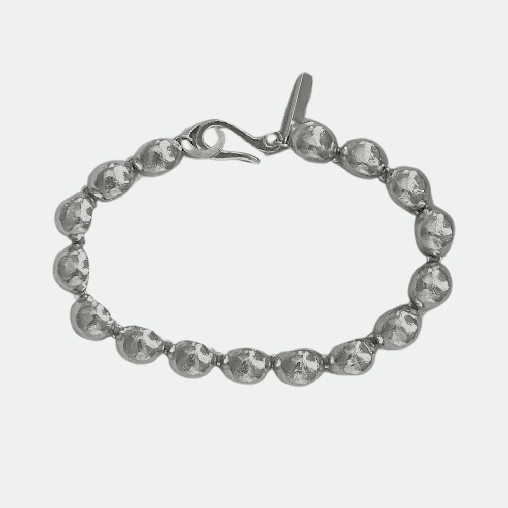 
                  
                    Silver bracelet with silver dome pendent beads on a white background
                  
                