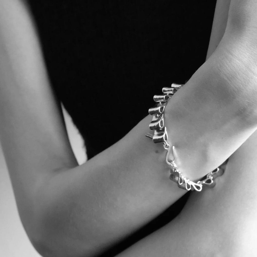 
                  
                    Close-up of a person's arm wearing a silver structural bracelet
                  
                