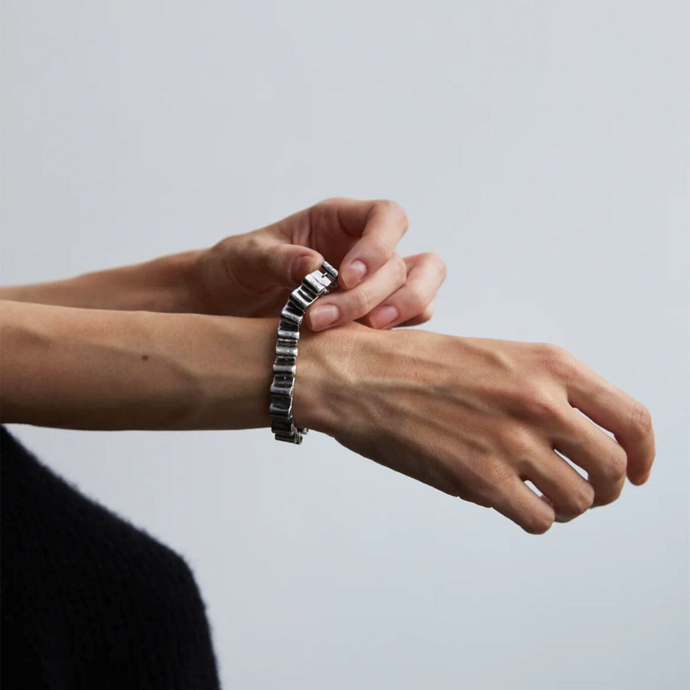 
                  
                    Person wearing a silver chunky bracelet on a plain background
                  
                