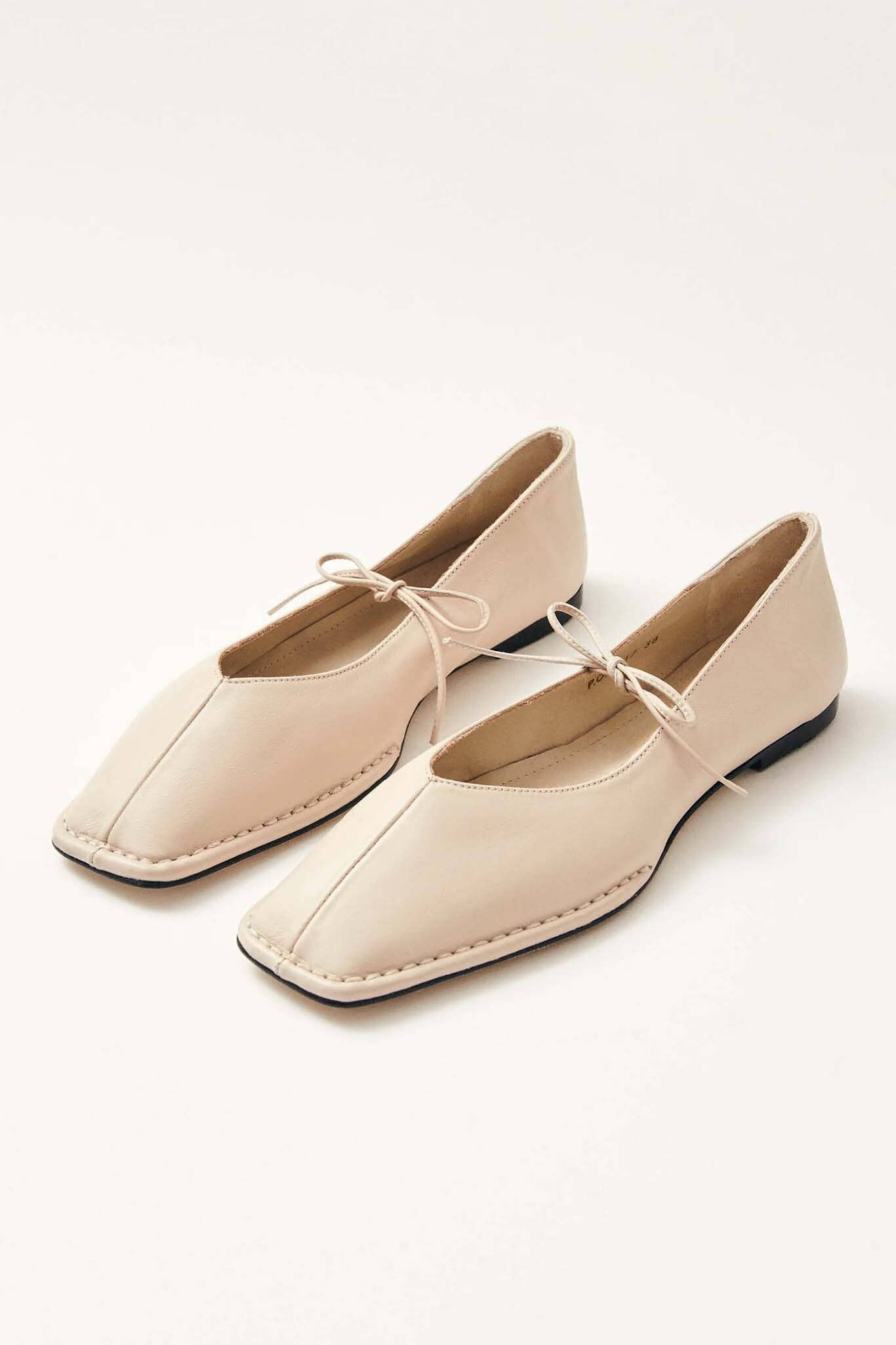Pair of cream ballet flats on a white background