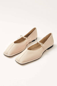 Pair of cream ballet flats on a white background
