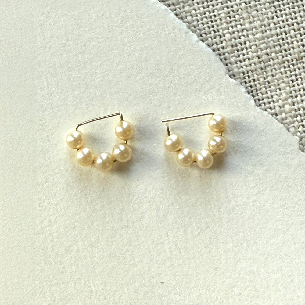 Pair of pearl hoop earrings on a textured fabric background