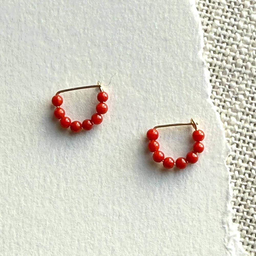 Pair of red beaded hoop earrings on a light background
