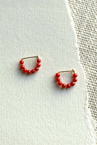 Pair of red beaded hoop earrings on a light background