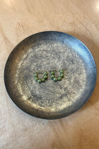Green beaded hoop earrings on a metallic plate with a wooden background