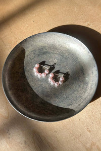 Pair of pink pearl hoop earrings on a dark stone surface