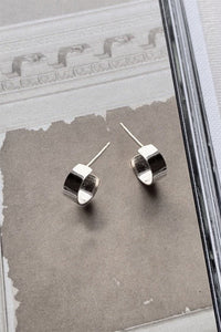 Silver hoop stud earrings on a textured gray surface