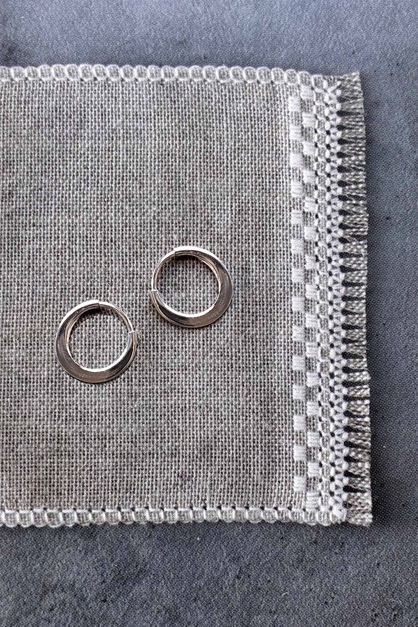 Two silver hoops on a textured gray fabric surface