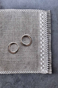 Two silver hoops on a textured gray fabric surface