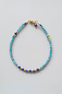 Bracelet with blue and gold beads on a light gray background