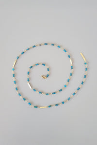Necklace with blue beads and gold accents on a gray background