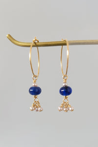 Pair of gold earrings with blue beads and pearl drops on a gray background