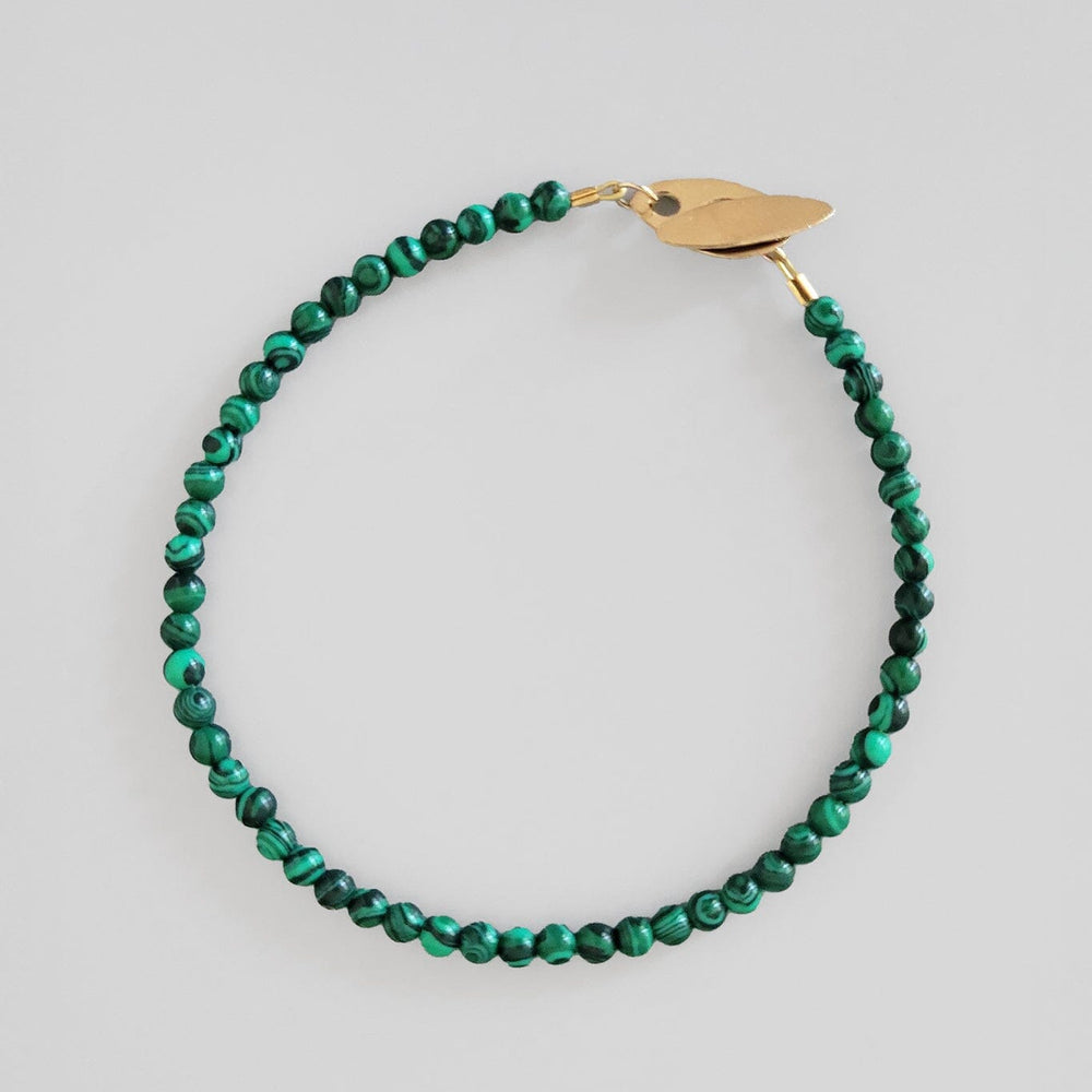 
                  
                    Green beaded bracelet with a gold clasp on a light gray background
                  
                