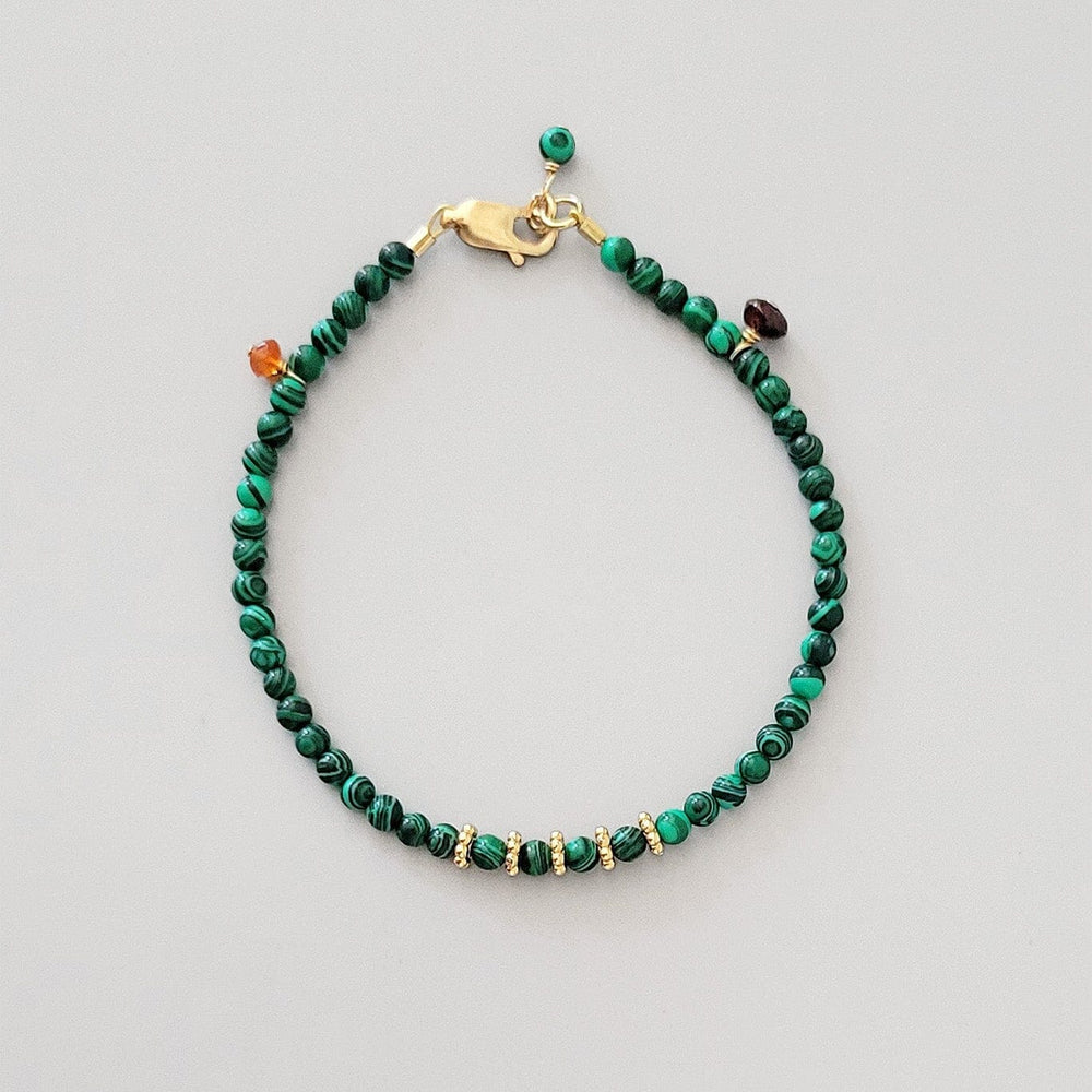 Green beaded bracelet with gold clasp on a light gray background