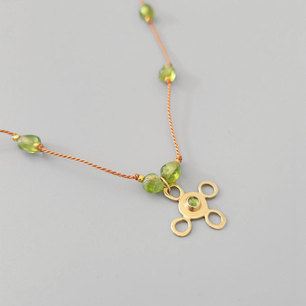 
                  
                    Necklace with green beads and a gold pendant on gold, silk rope
                  
                