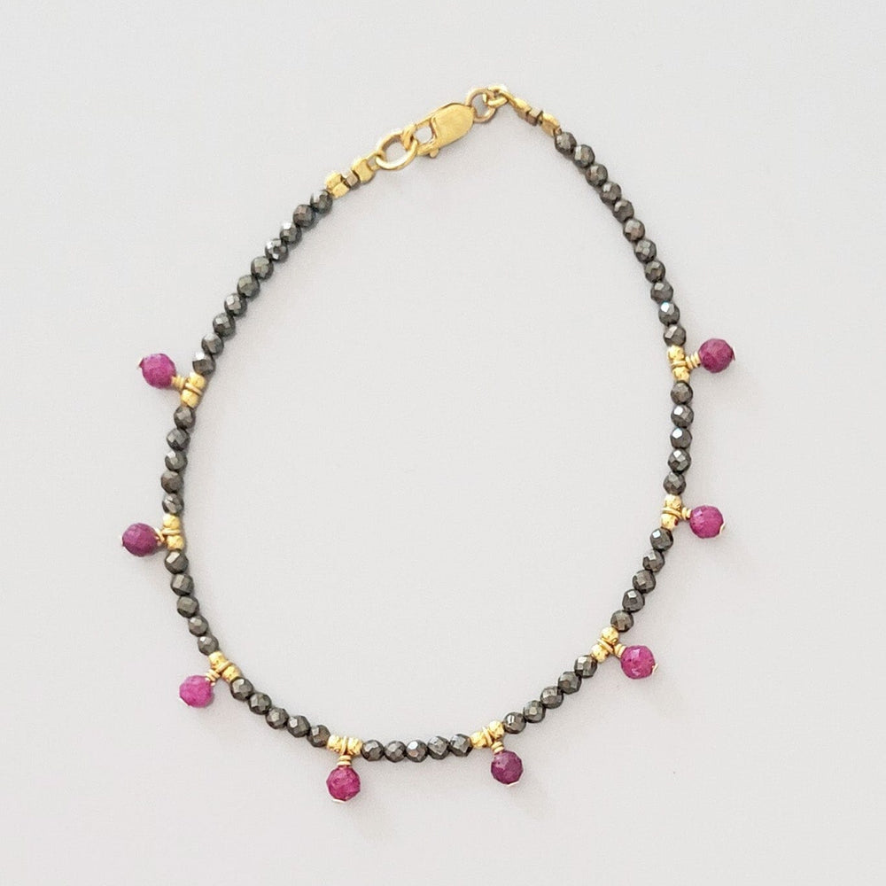 Bracelet with ruby and gray pyrite faceted beads on a light gray background
