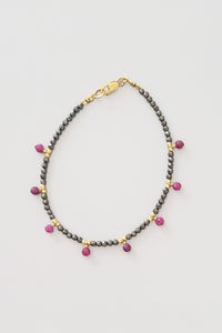 Bracelet with ruby and gray pyrite faceted beads on a light gray background