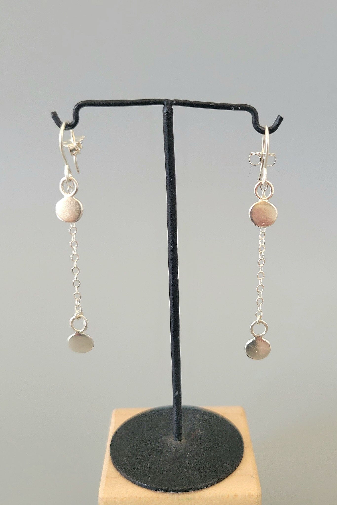 Pair of earrings on a black stand with a gray background