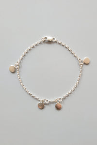 Silver bracelet with small round pendants on a gray background