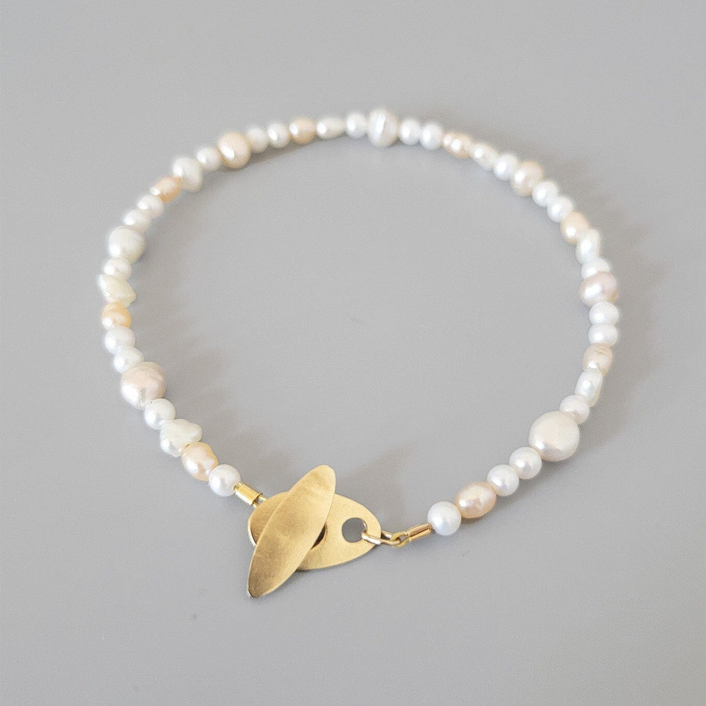 Pearl bracelet with a gold clasp on a gray background