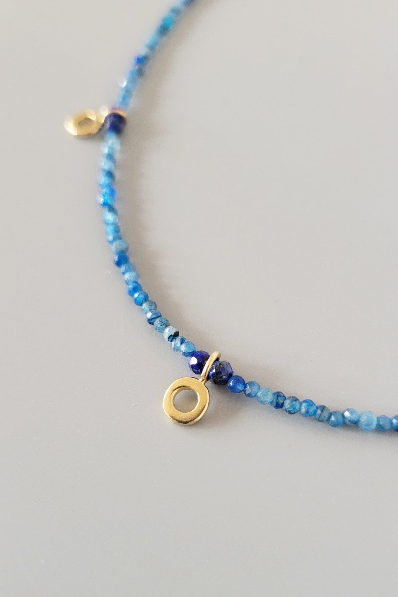 Blue beaded necklace with gold accents on a gray background