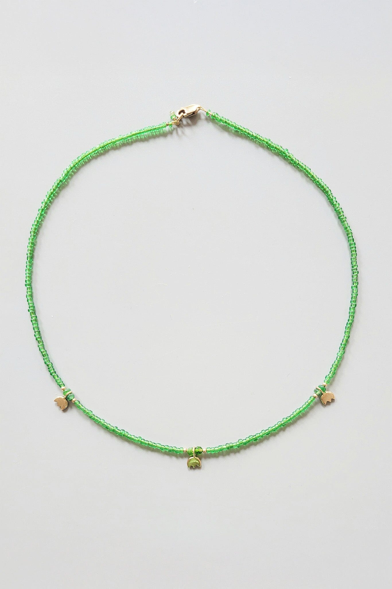Green beaded necklace on a light gray background