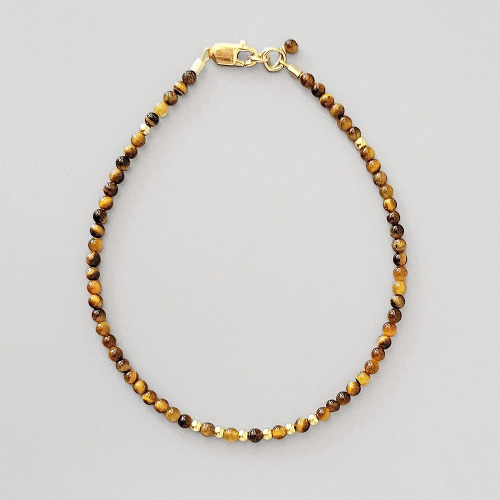 Beaded tigers eye bracelet with gold clasp on a gray background