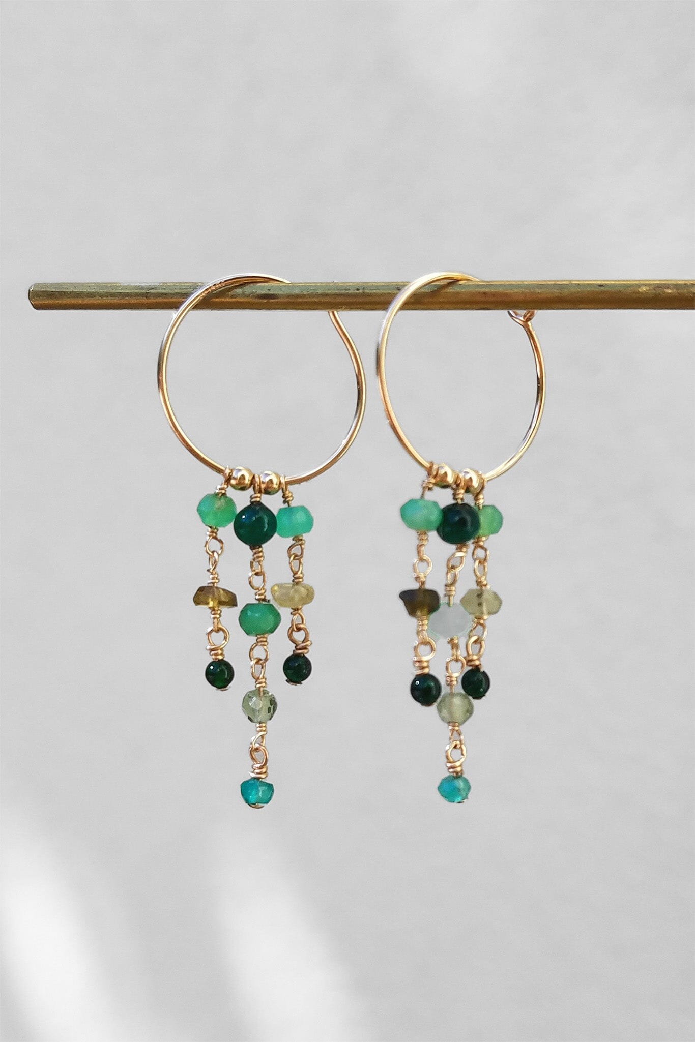 14k gold filled hoops featuring strands of green gemstones such as adventurine and apatite. Available at M.Patmos in Brooklyn New York.