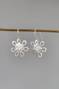 Silver flower-shaped earrings on a gray background