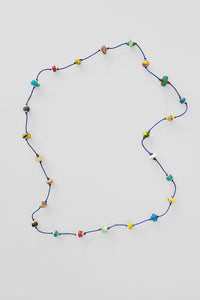 A knotted necklace with dark blue cord and multicolored beads displayed against a white background.