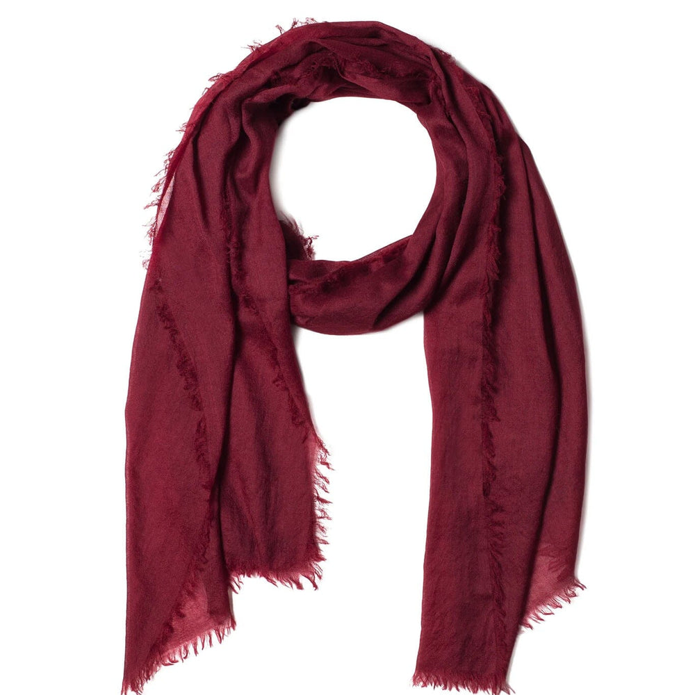 Red cashmere and merino scarf with frayed edges on a white background