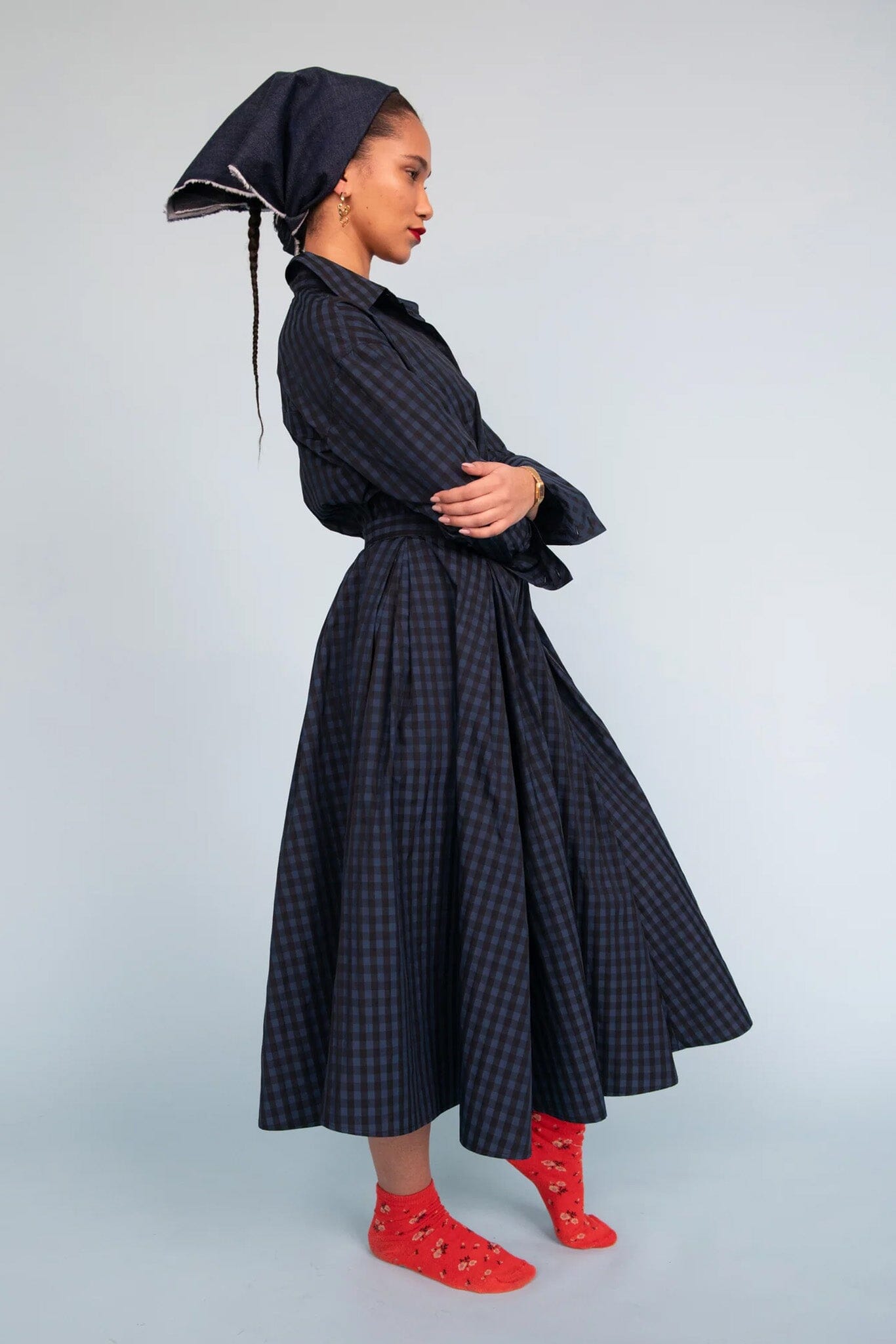 Woman wearing a dark checkered skirt with a head scarf against a light background