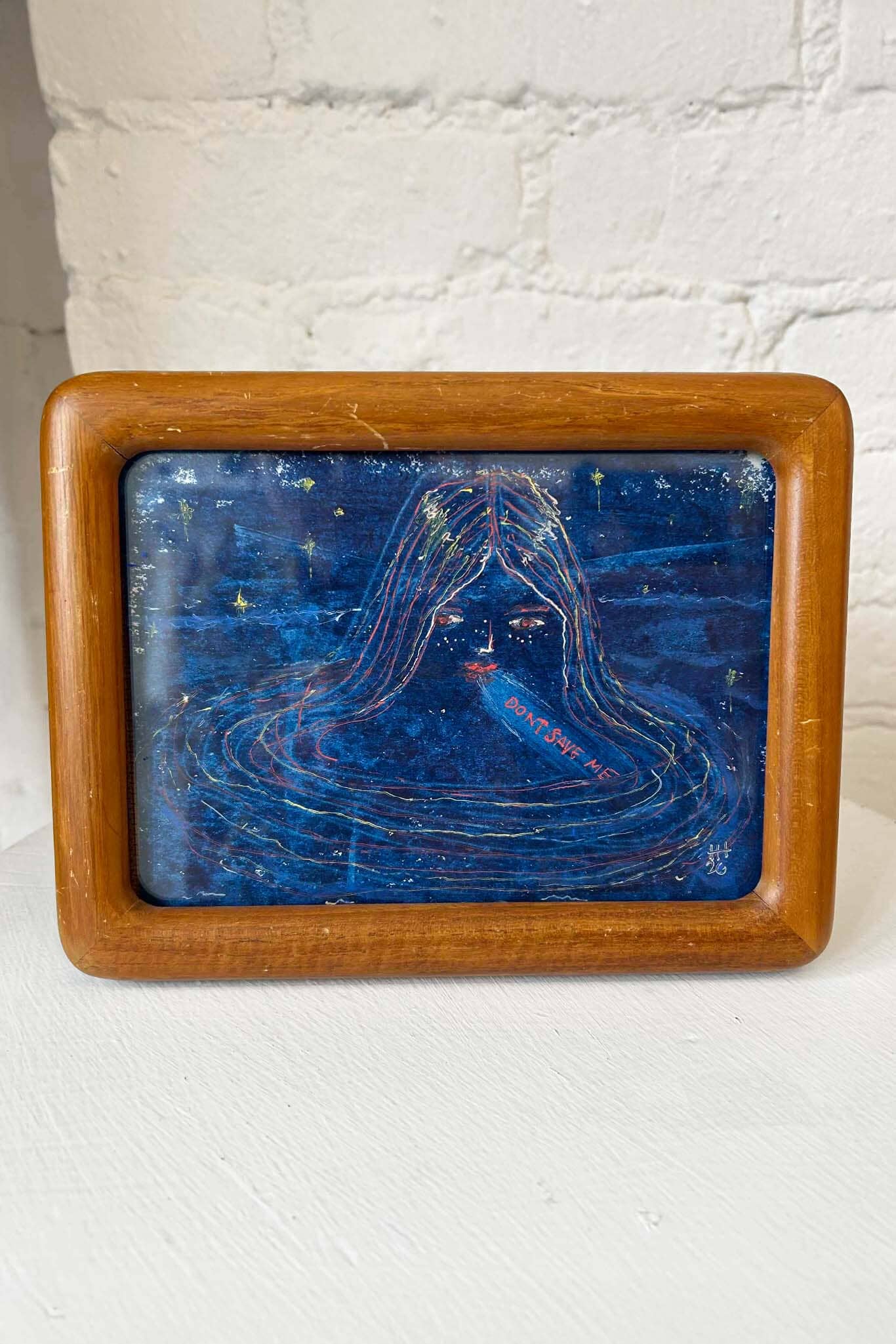 Framed artwork with a blue abstract design on a white surface