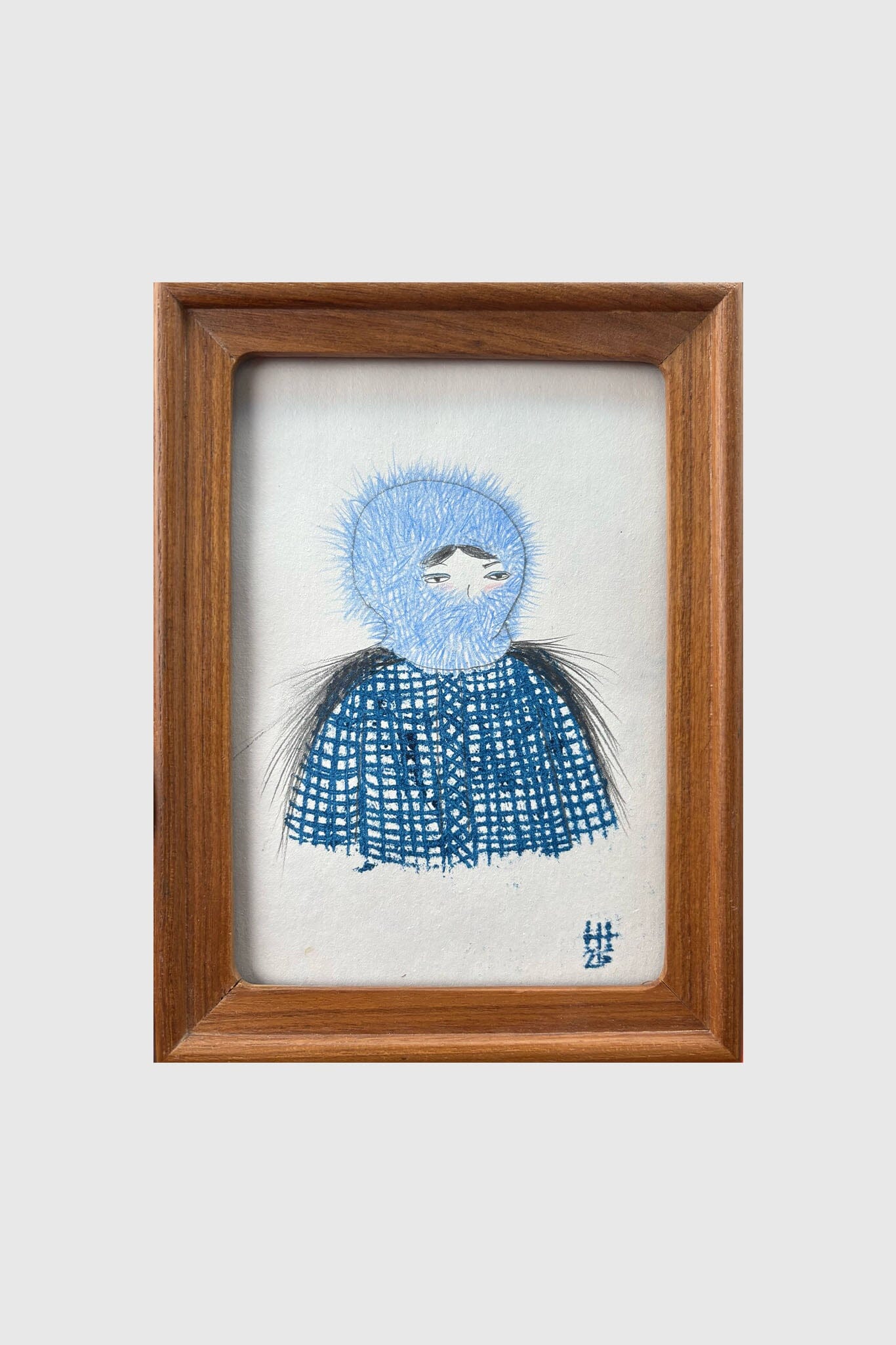 Framed artwork of a blue and white embroidered character on a white background