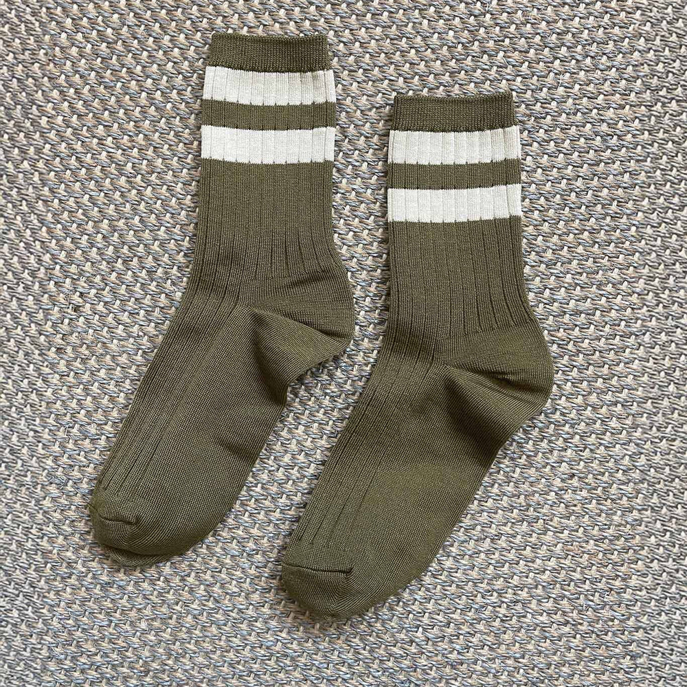 Pair of army green socks with white stripes on a textured gray background