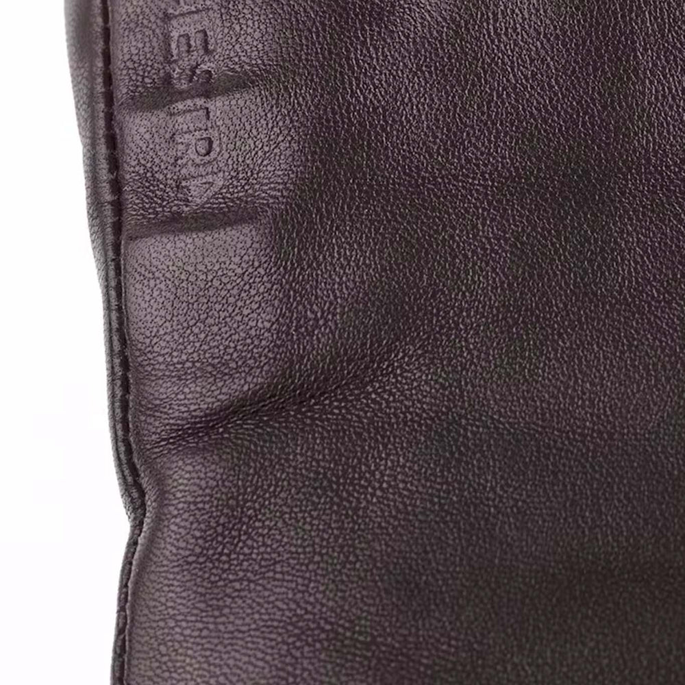 Close-up of a dark brown leather glove with 'Hestra' branding.