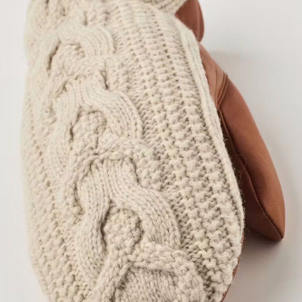 Knitted beige mitten with brown leather lining on a white background
