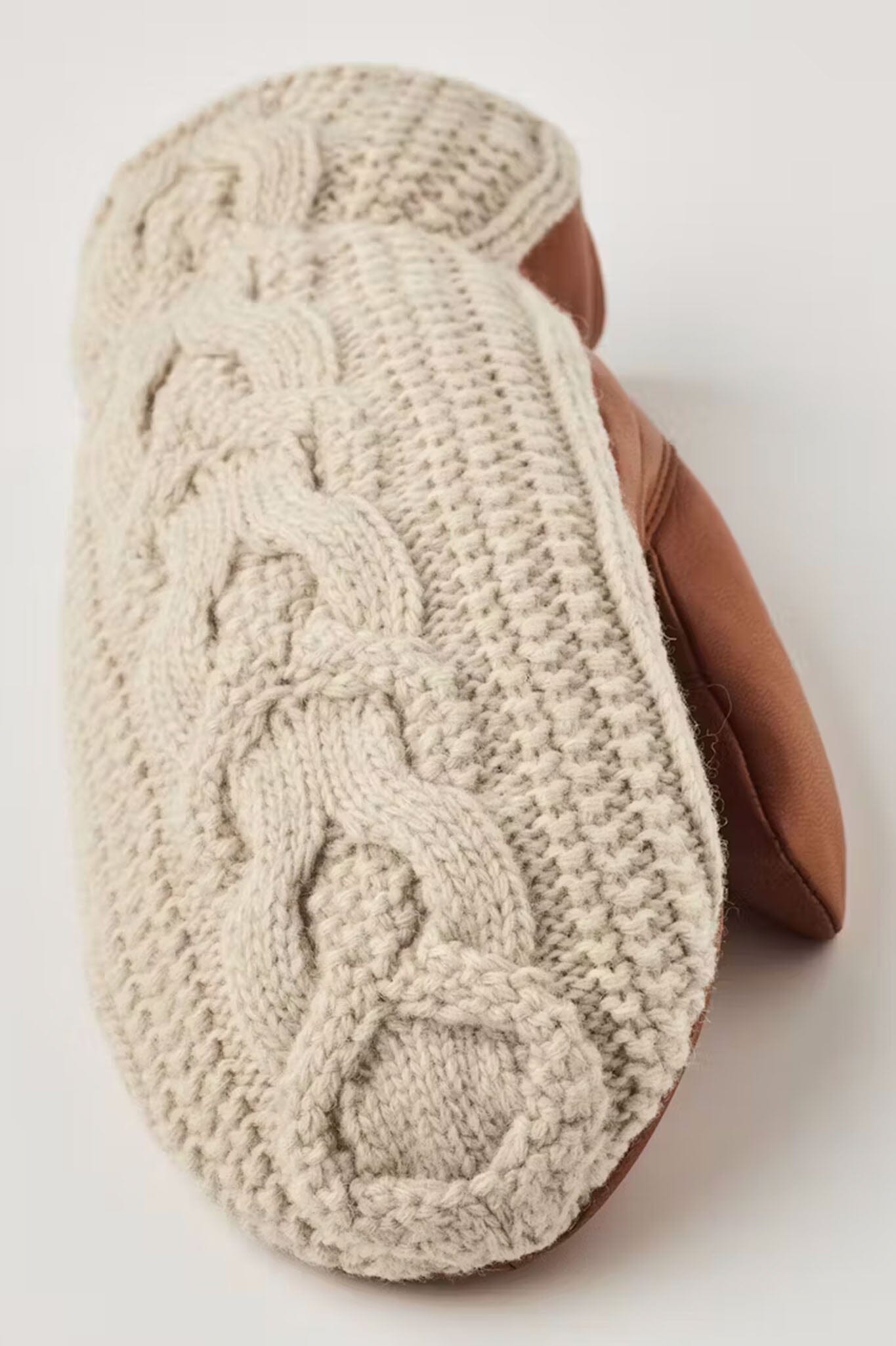 Knitted beige mitten with brown leather lining on a white background