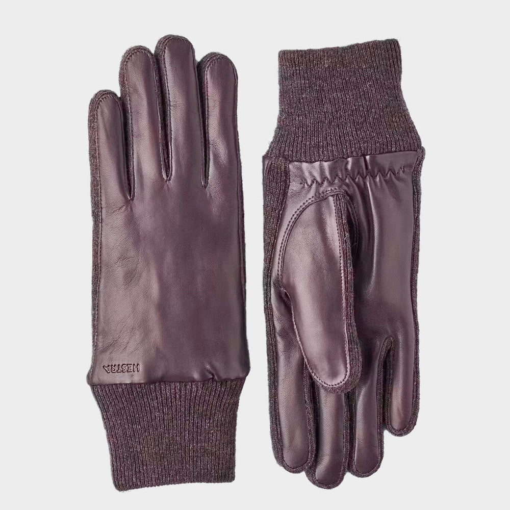Pair of leather gloves with knit cuffs on a light gray background