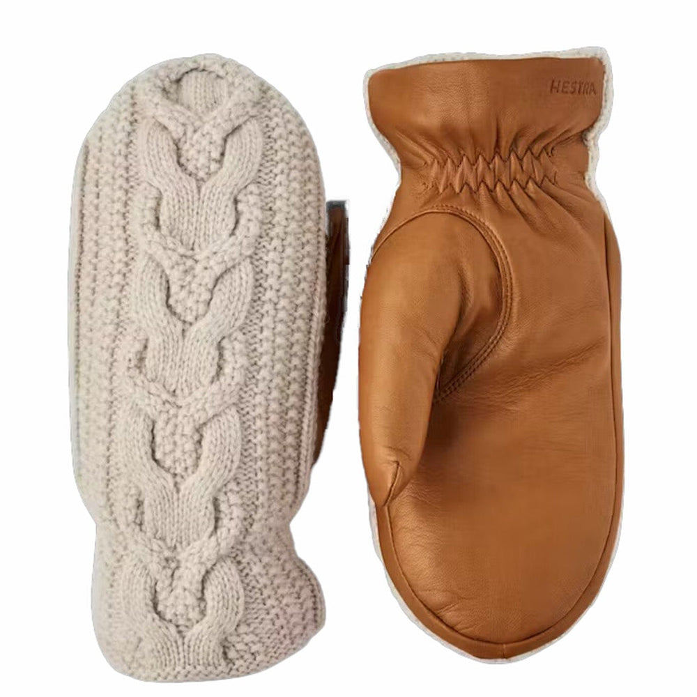 Pair of mittens, one beige knitted and one brown leather, on a white background