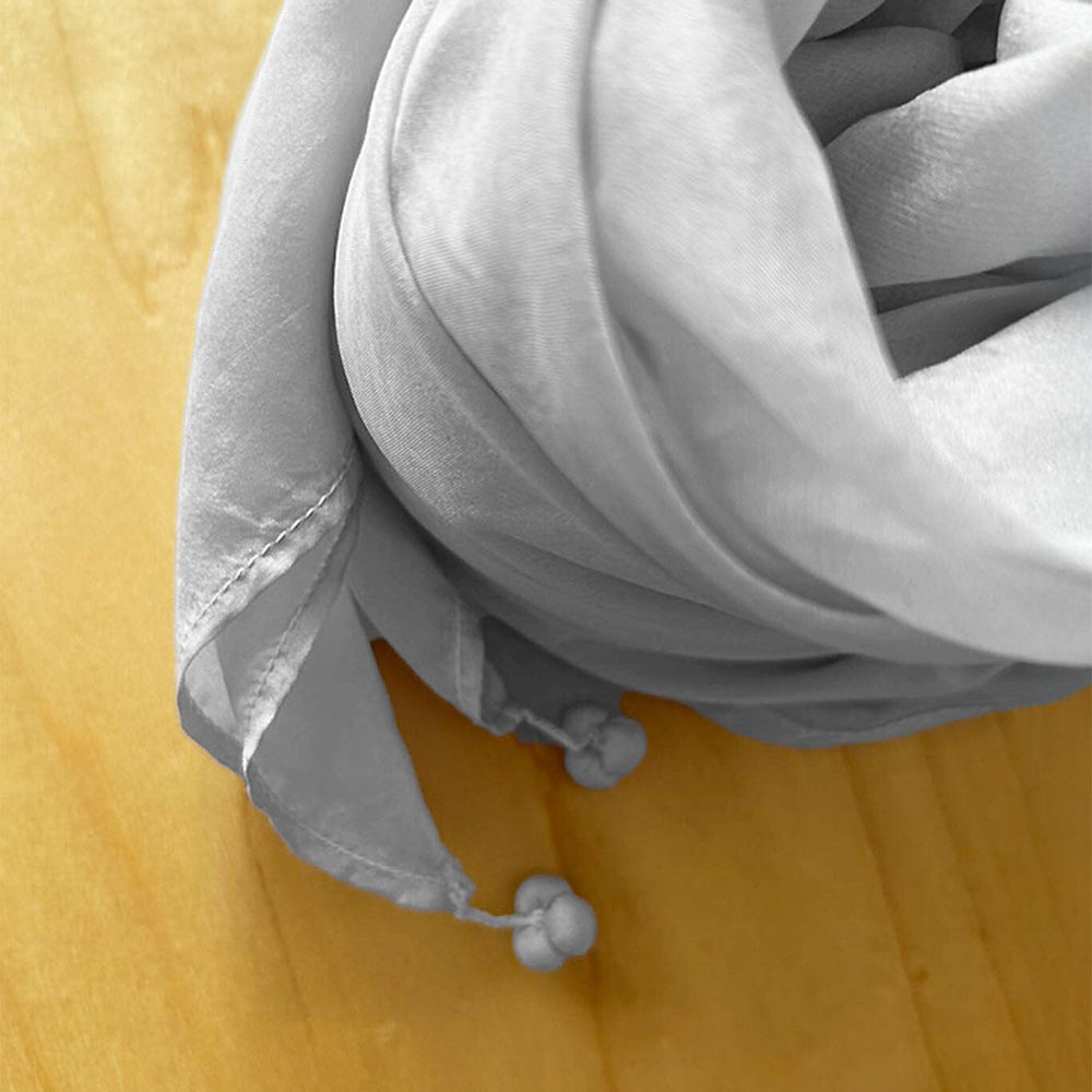 tassels on the edge of a silver grey silk scarf