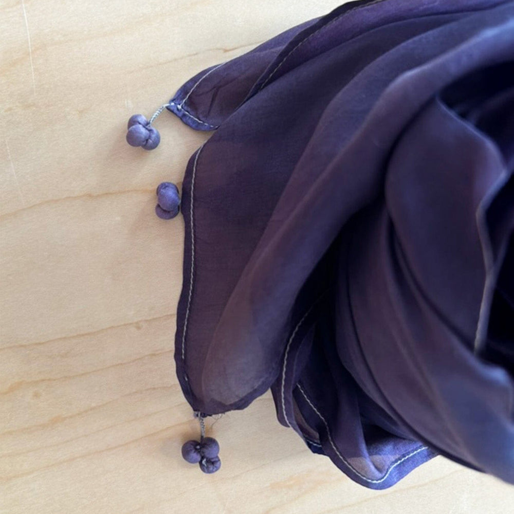 Tassel details on the corners of a purple silk scarf