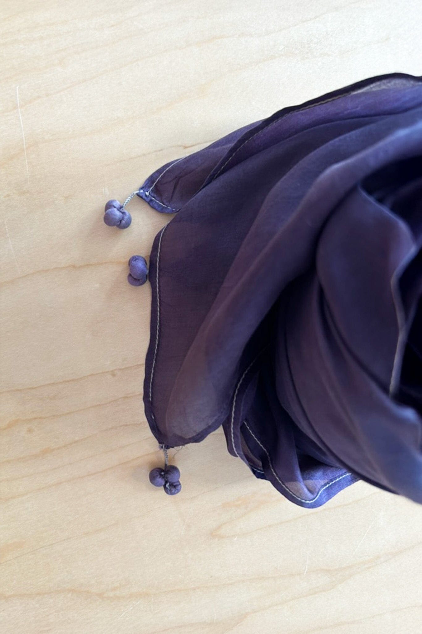 Tassel details on the corners of a purple silk scarf