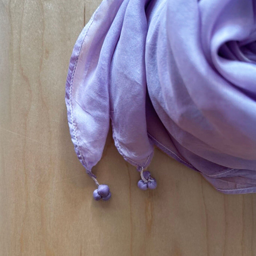 Purple scarf with tassels on a wooden surface