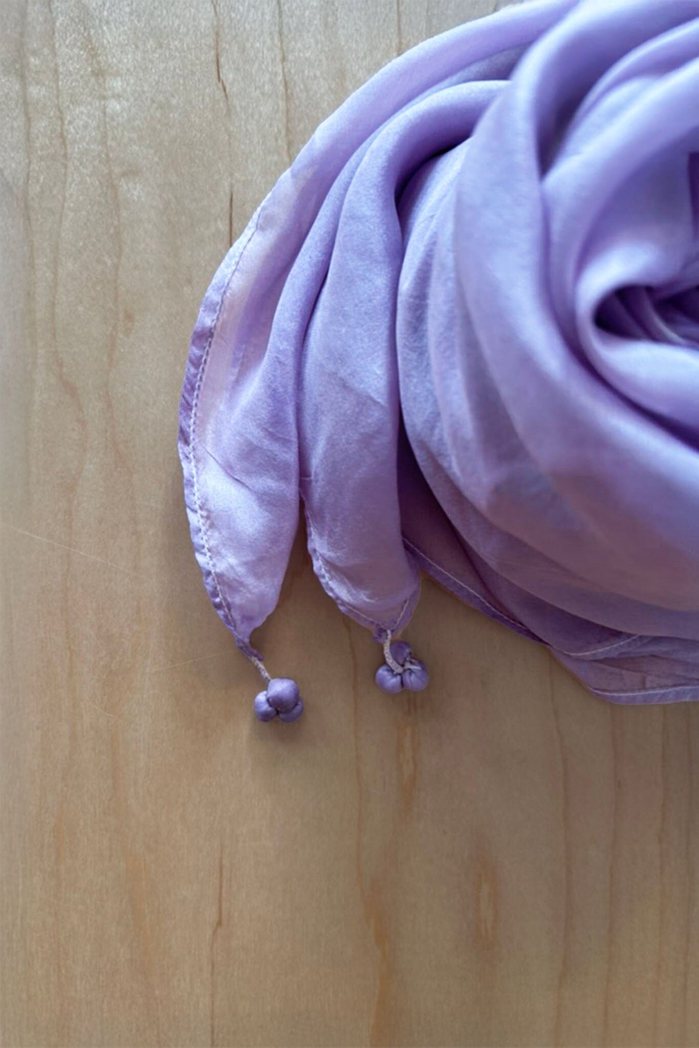 Purple scarf with tassels on a wooden surface