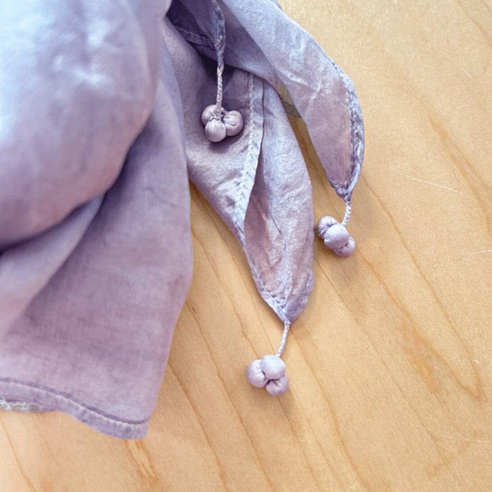 Purple silk scarf tassels on a wooden surface