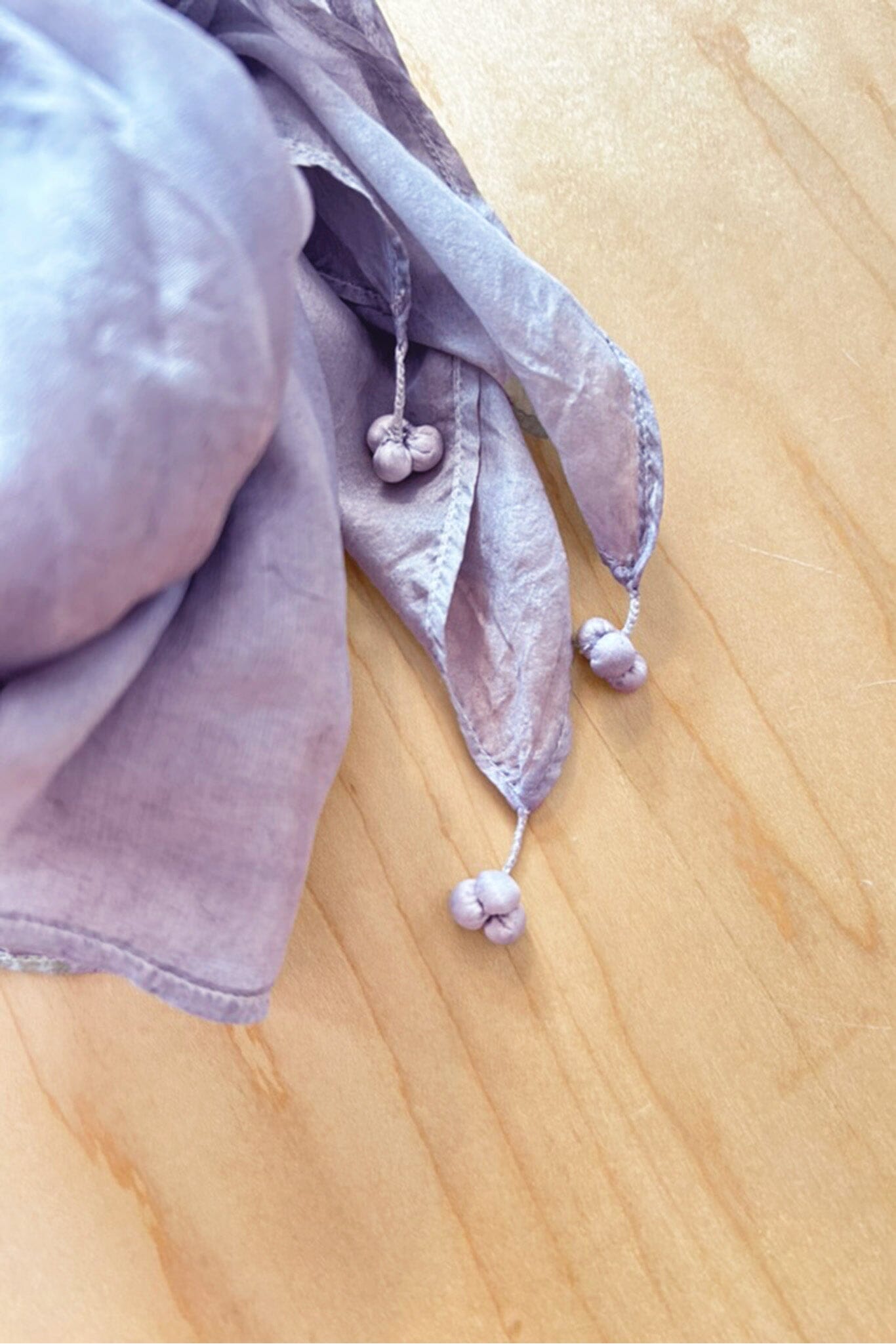 Purple silk scarf tassels on a wooden surface