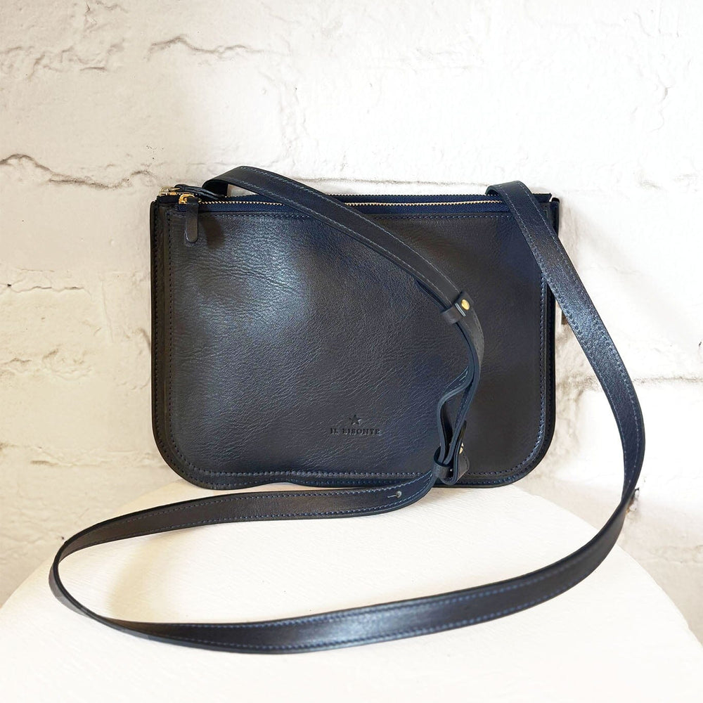 Navy leather crossbody bag on a light marble background