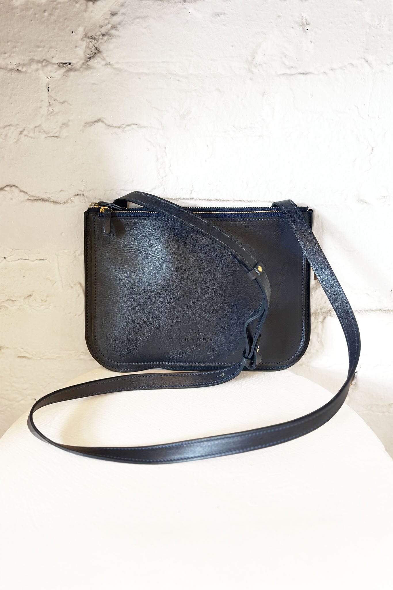 Navy leather crossbody bag on a light marble background