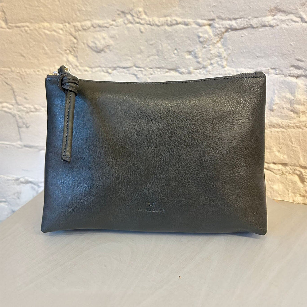 Black leather zipper pouch on a light gray surface with a textured white wall background